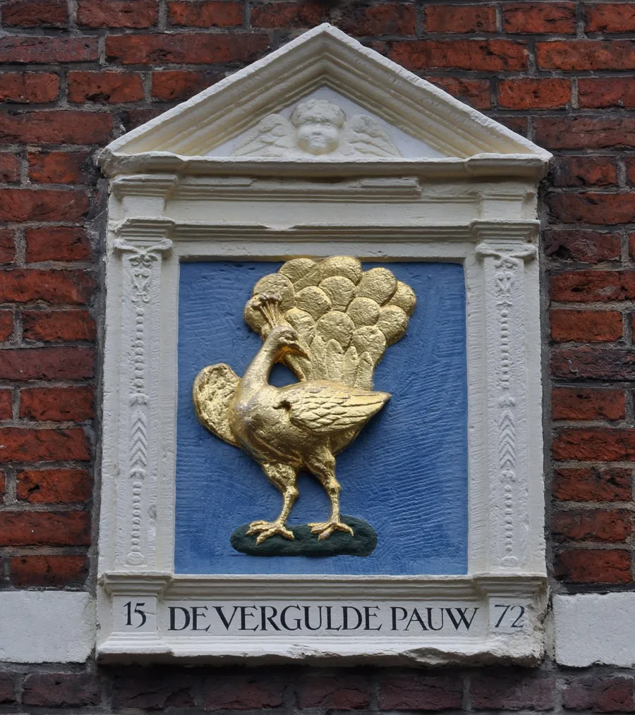 Een gevelsteen met een vergulde pauw.